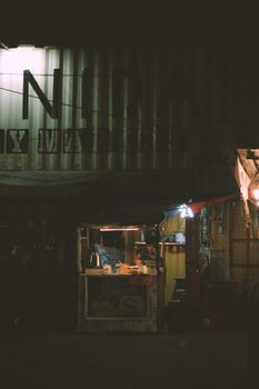 Illuminated city street food stall at night with a dark atmospheric vibe.