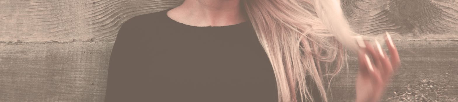 Close-up portrait of a woman with long, flowing blonde hair against a textured background.