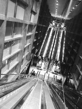 城市环境中，现代自动扶梯的黑白图像倒映出建筑的轮廓