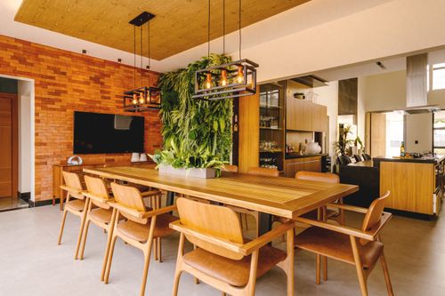 Free A stylish dining room featuring a wooden table, hanging greenery, and brick wall decor. Stock Photo