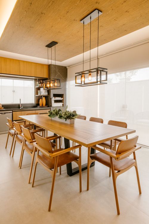 Free Spacious modern dining room featuring wooden table and chairs, pendant lights, and a bright airy feel. Stock Photo