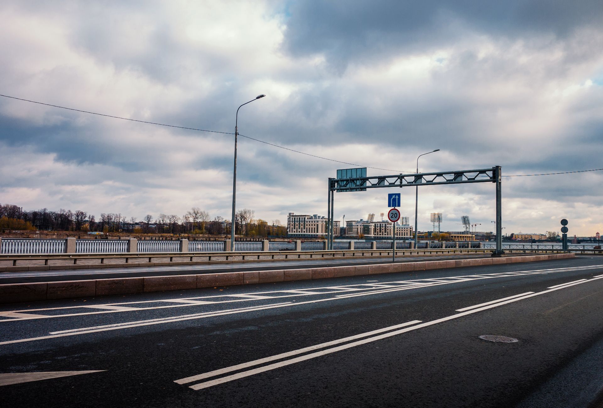 An empty main street of a modern city under a cloudy sky.
