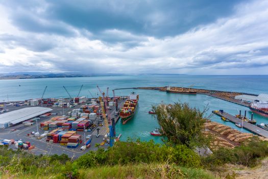 Photo by 飞 谢 A busy ocean port with cargo ships, containers, and cranes under a dramatic cloudy sky.