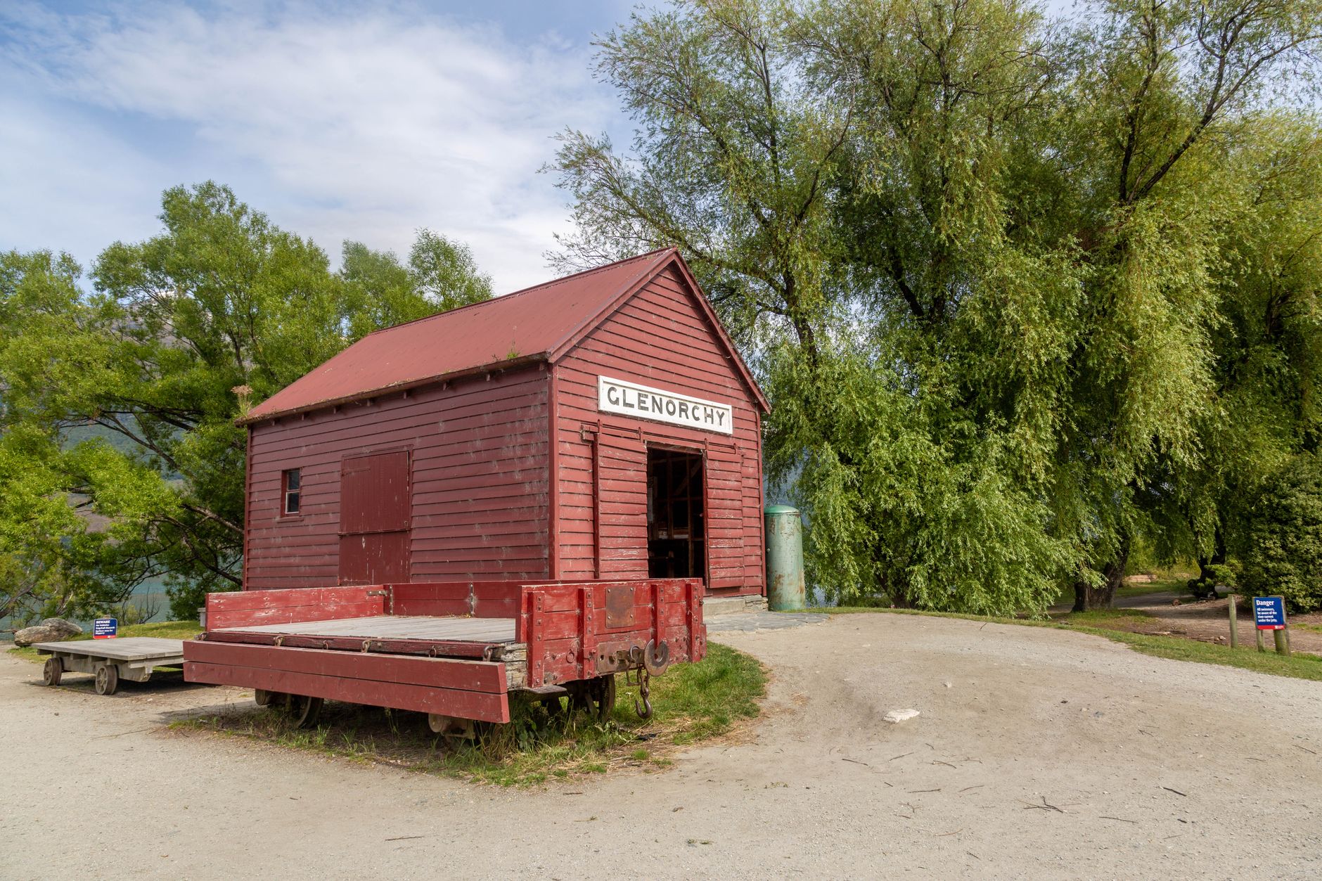 A rustic red barn in Glenorchy, surrounded by lush greenery and open skies.