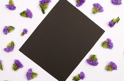 A Black Piece of Paper Surrounded by Purple Flowers