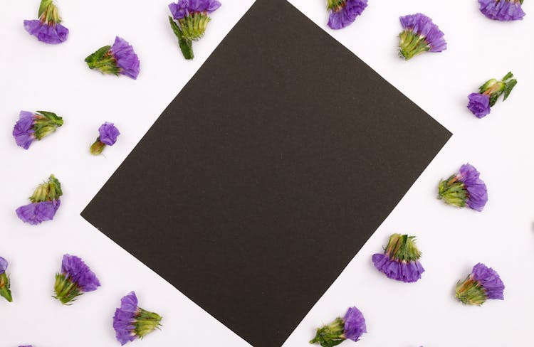 A Black Piece Of Paper Surrounded By Purple Flowers