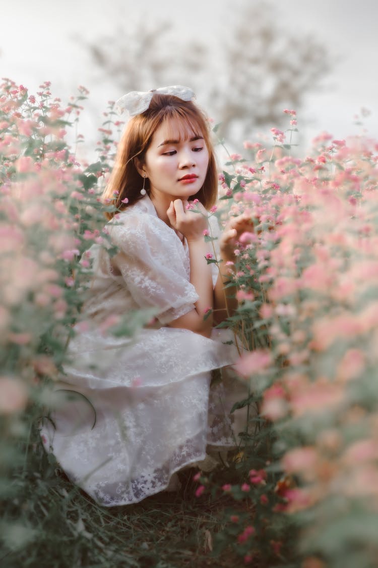 Woman Wearing Lace Dress Crouching In Garden