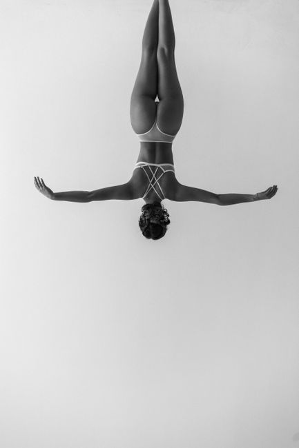 Elegant black and white image of a woman in lingerie performing a pose upside down.