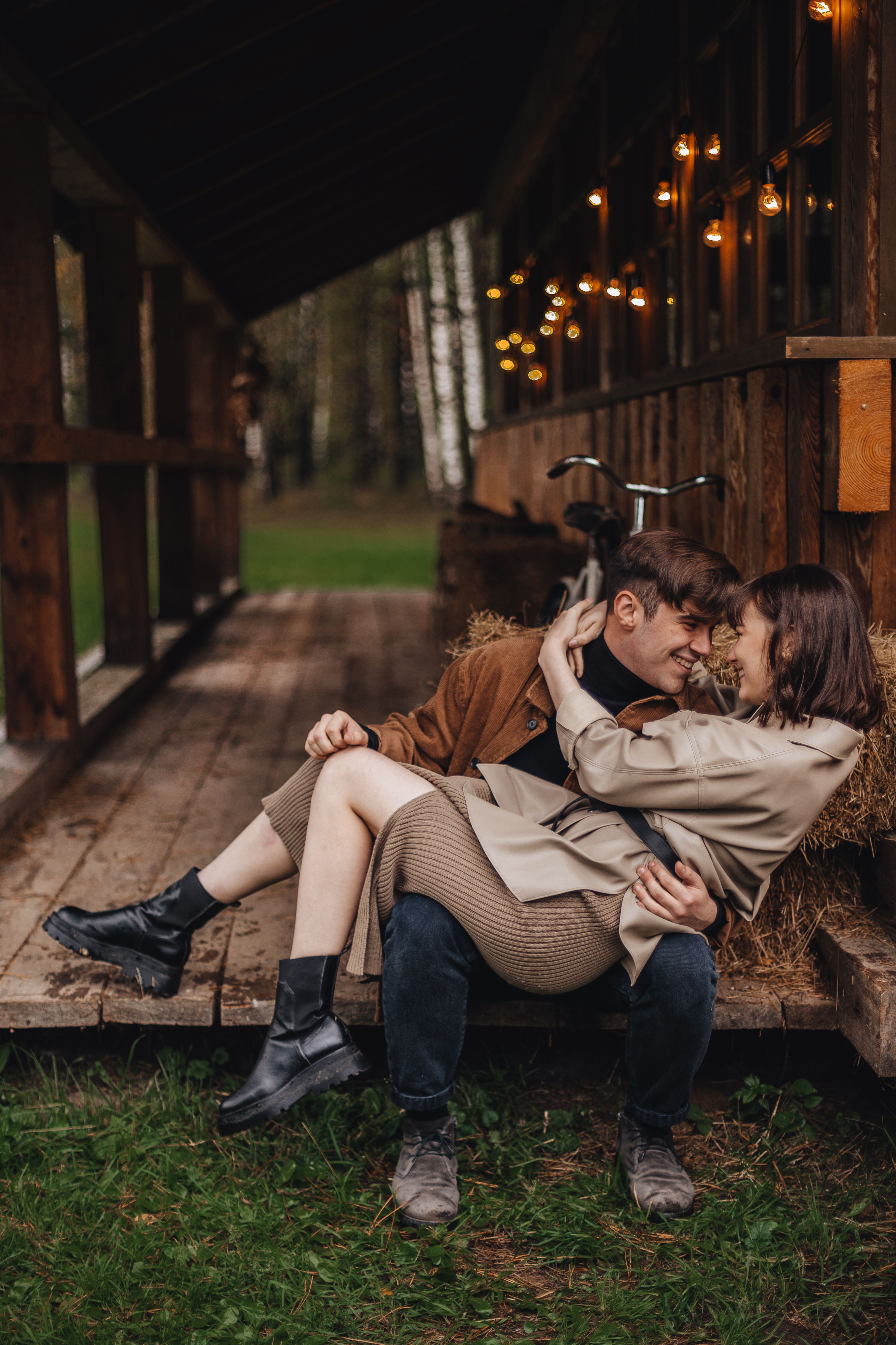 Cozy couple embracing in warm clothing outside a rustic cabin during autumn.