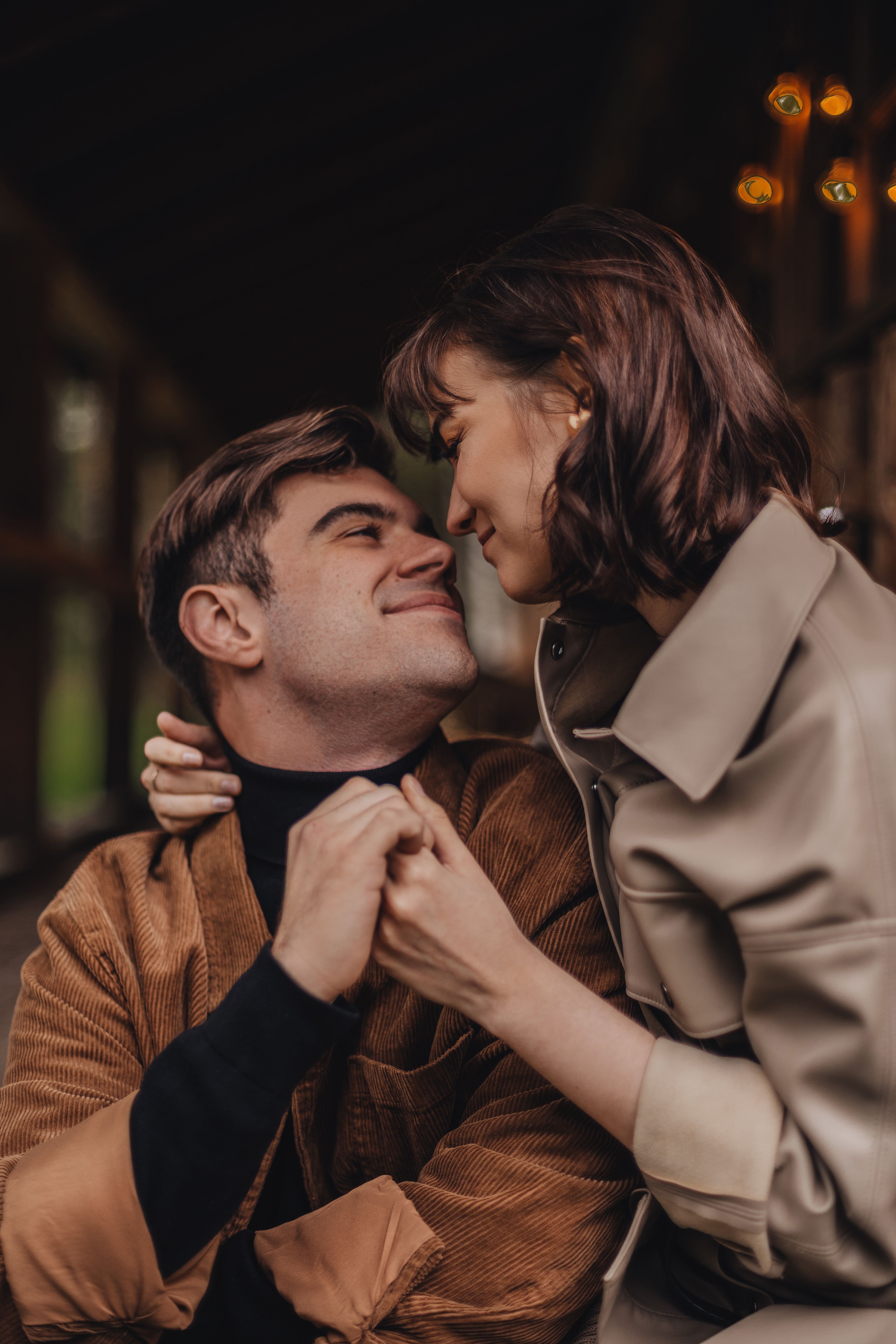 A couple lovingly gazes at each other while embracing in warm, autumn clothing.