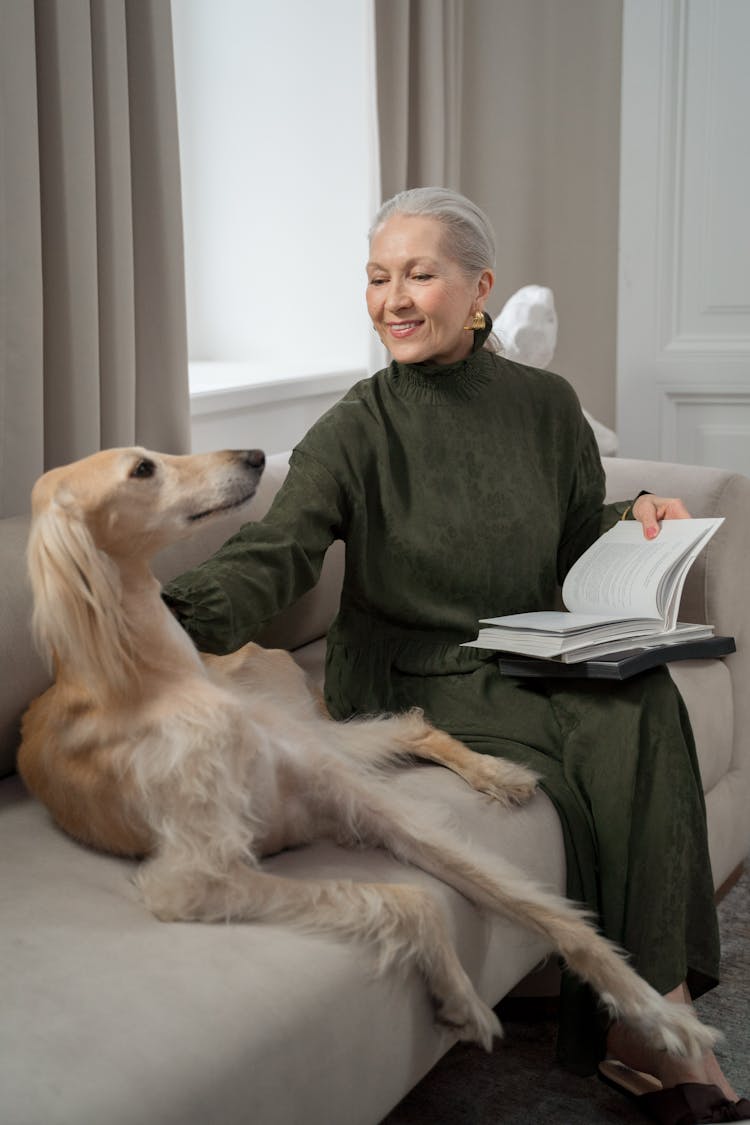 Elderly Woman In Olive Dress Petting Her Greyhound Dog