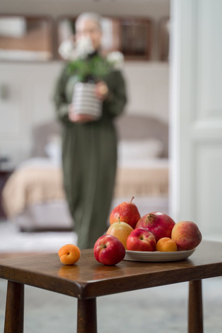 Plate Of Fruits On Table With Out Of Focus Silhouette Of Woman In Background