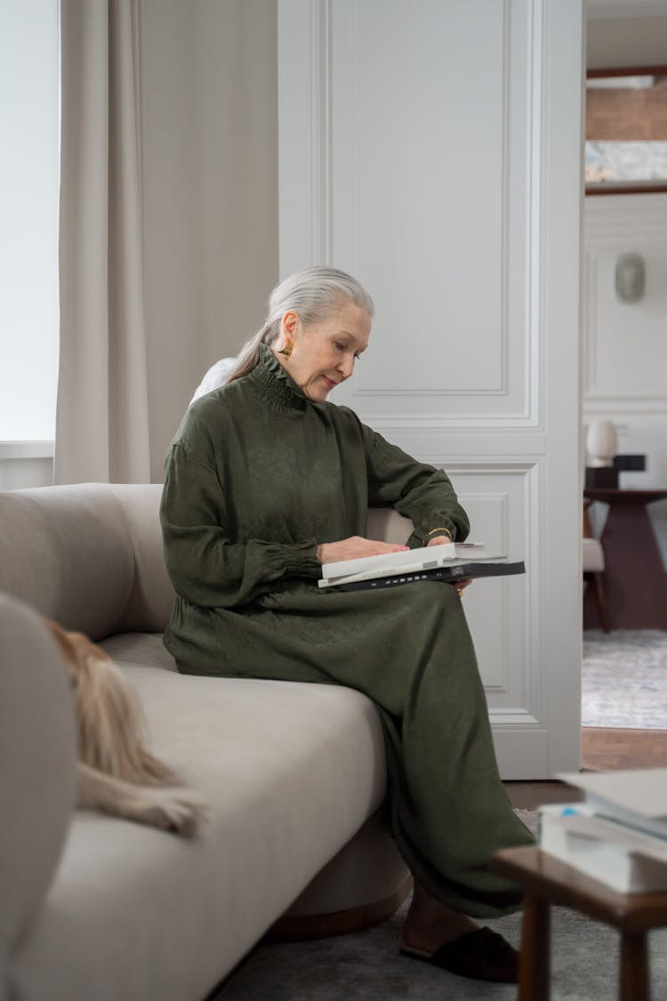 Neat Senior Woman With Grey Hair Reading Book In Her Room