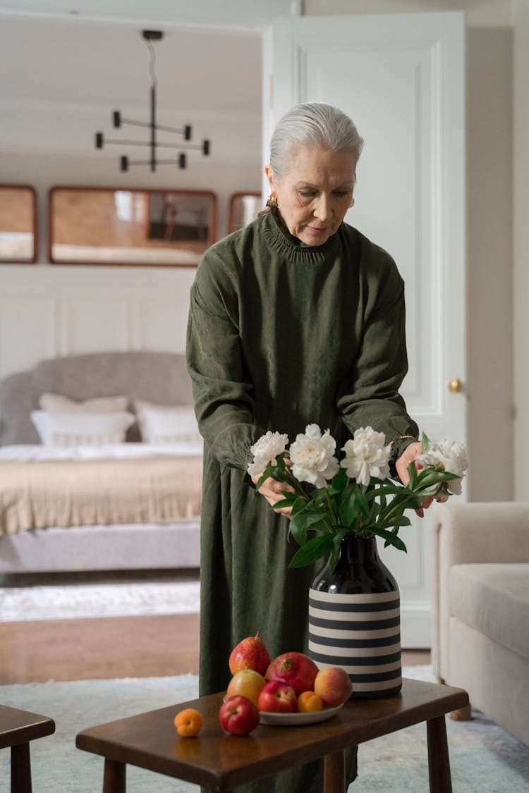 Elderly Woman Arranging Peonies In Vase