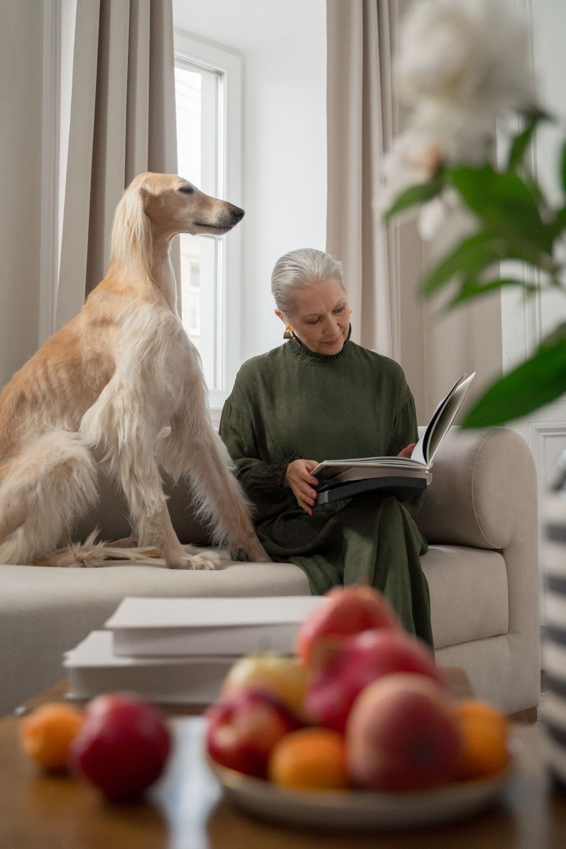 Mulher madura lendo em casa com seu cão por perto