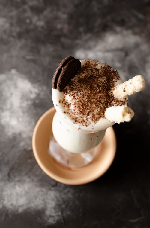 Free Top view of a creamy milkshake with chocolate shavings and a cookie on a dark background. Stock Photo