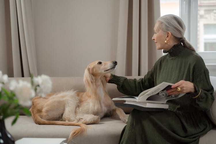 Senior Lady Talking To Her Dog Laying On Sofa