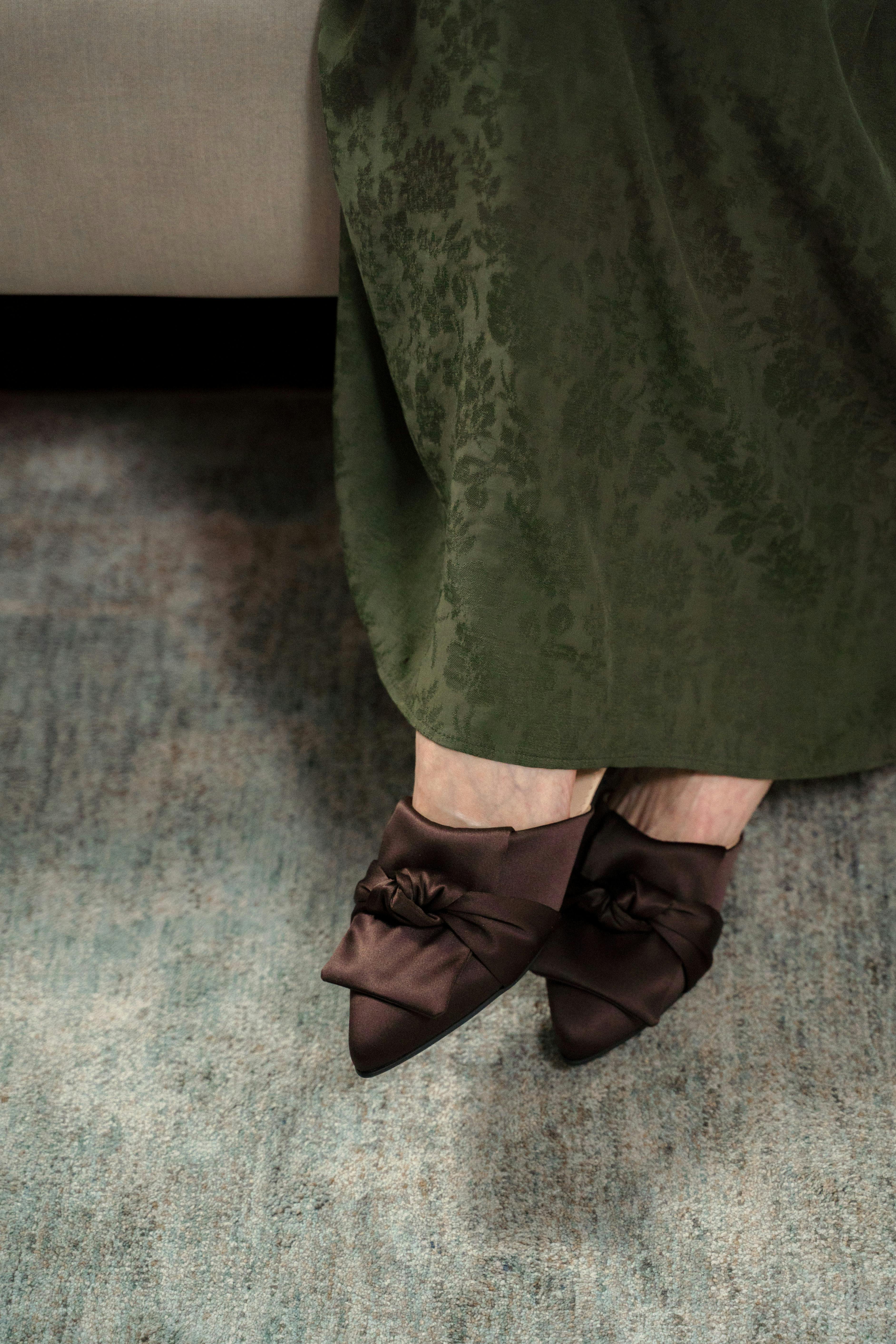 unrecognizable female feet in brown velvet mules