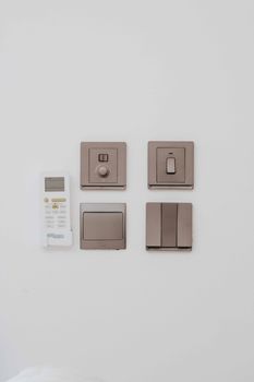 A clean, minimalist arrangement of a remote control and four light switches against a white wall.