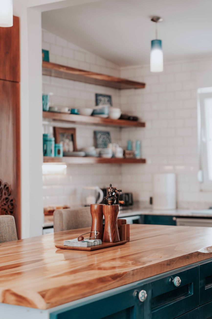 A warm kitchen with timber shelving and a long counter designed for conversation rather than display.