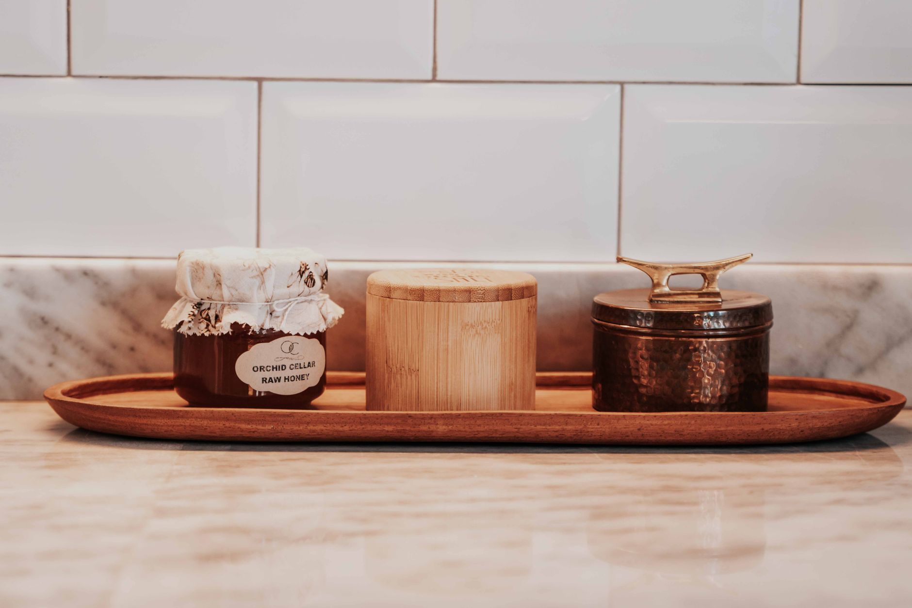 A cozy kitchen setting with a jar of raw honey and decorative containers on a tray.