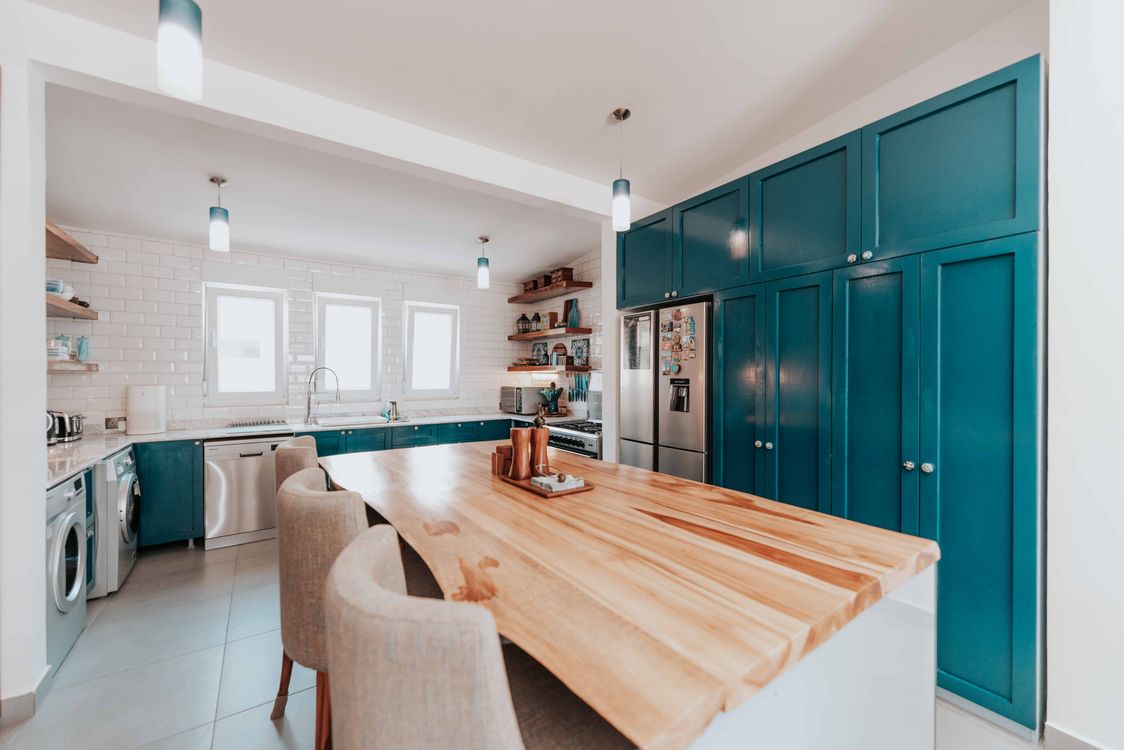 Architectural teal cabinetry balanced by a large wood island