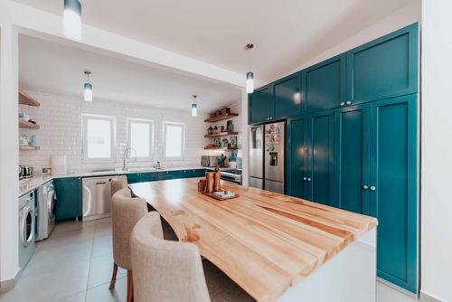 Free Spacious kitchen featuring teal cabinets, large wooden island, and modern appliances. Stock Photo
