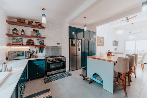 Free Spacious kitchen with blue cabinets, island, and modern appliances, highlighting a cozy dining setup. Stock Photo