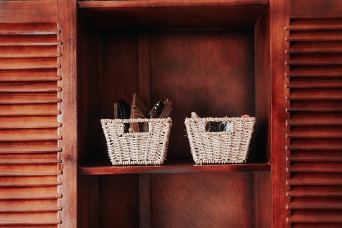 Two woven baskets on a wooden cabinet shelf — photo by Keegan Checks on Pexels