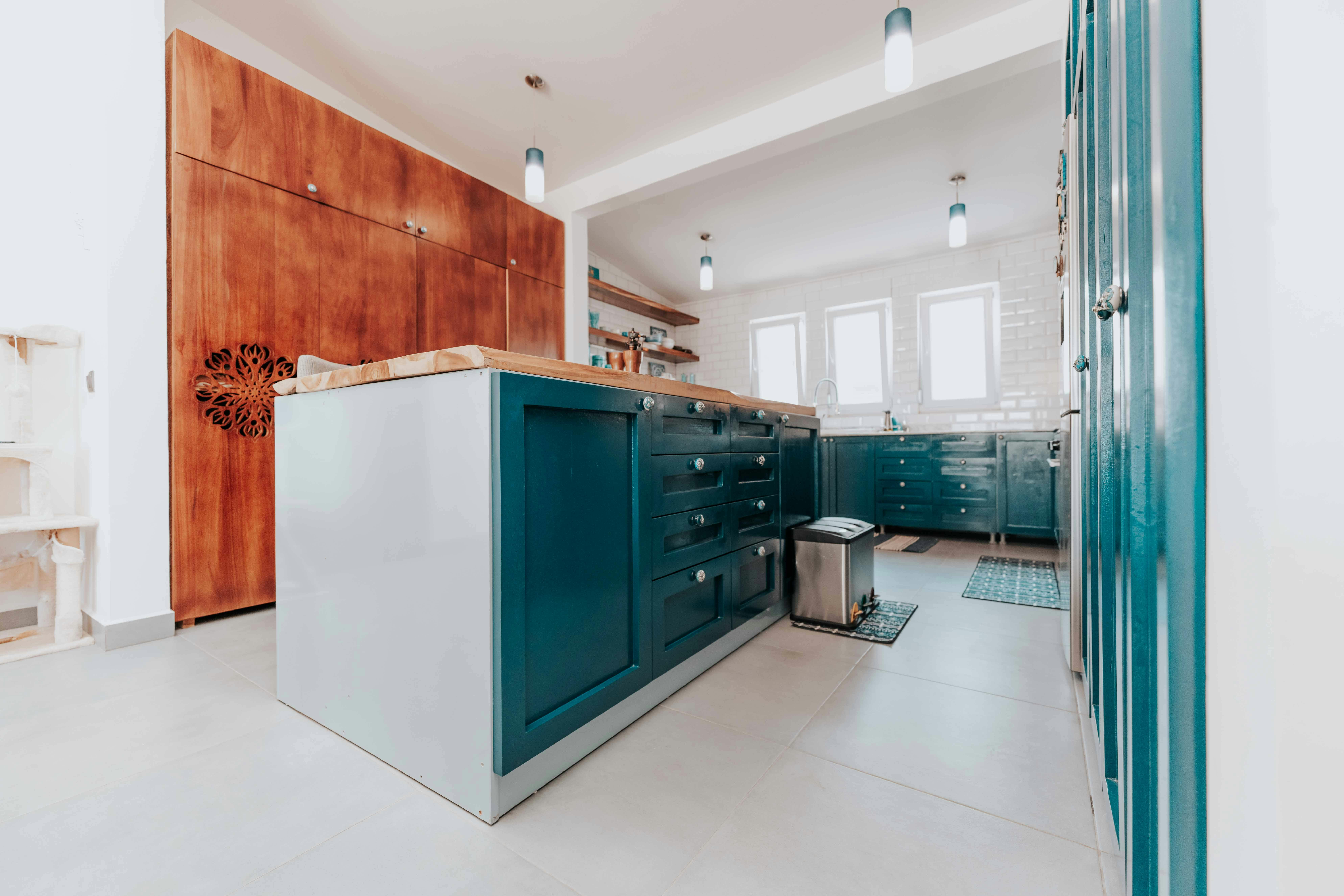 Pale Blue Kitchen Cabinets With White Quartz Countertops And Light Wood Open Shelving In A Bright, Airy Kitchen Setting