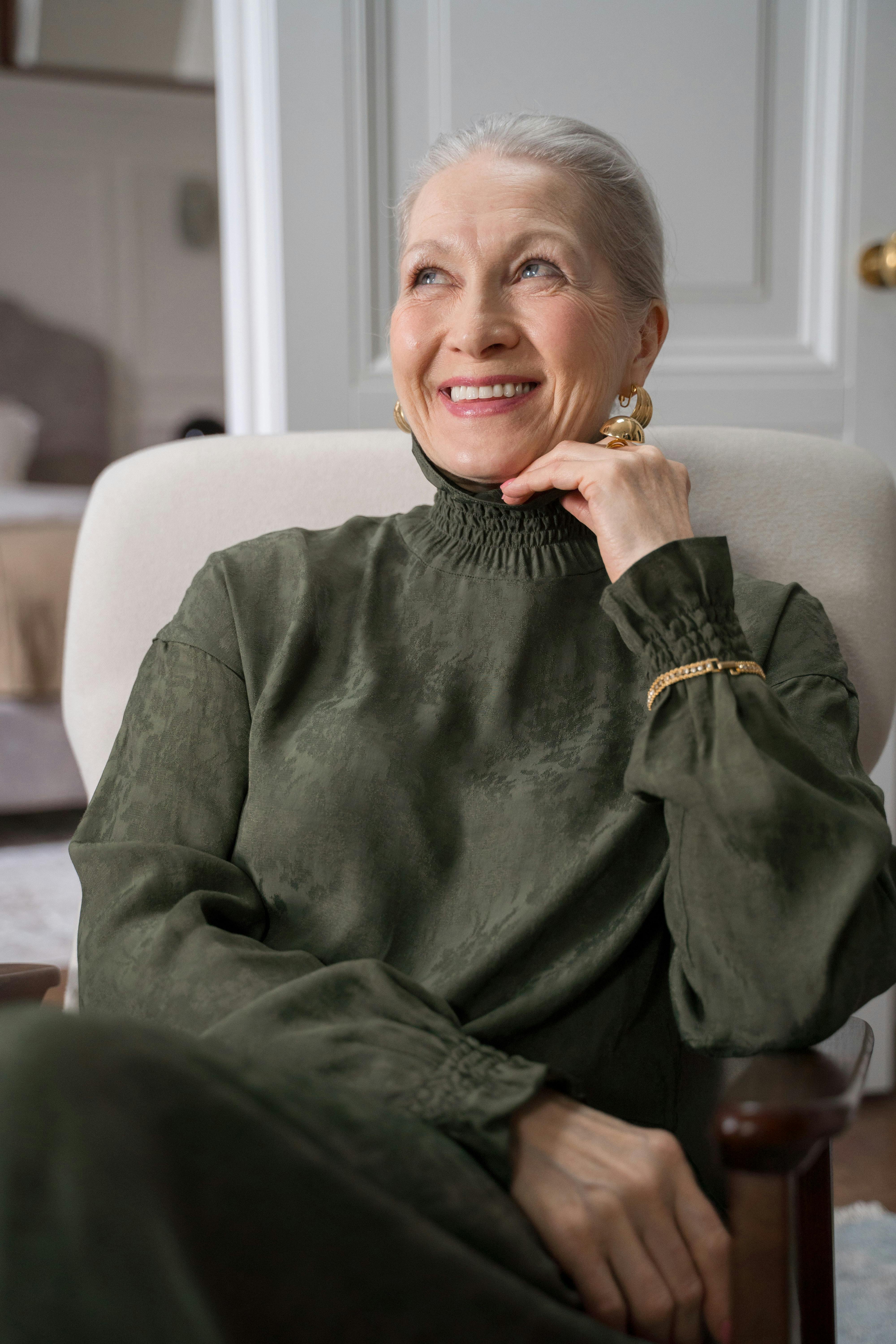 一位面带微笑的高级女士的肖像舒适地坐在室内，散发着优雅的气质