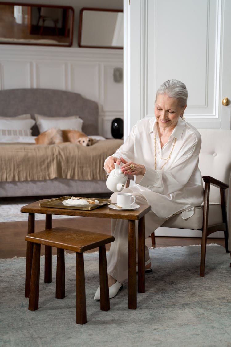 Elderly Woman Pouring A Tea At Home