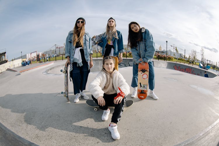 Group Of Teenage Girls Wearing Jackets Posing And Standing On Skate Park