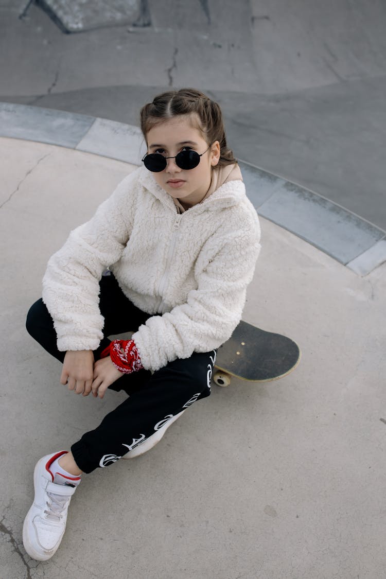 Kid In Fur Jacket Sitting On Skateboard