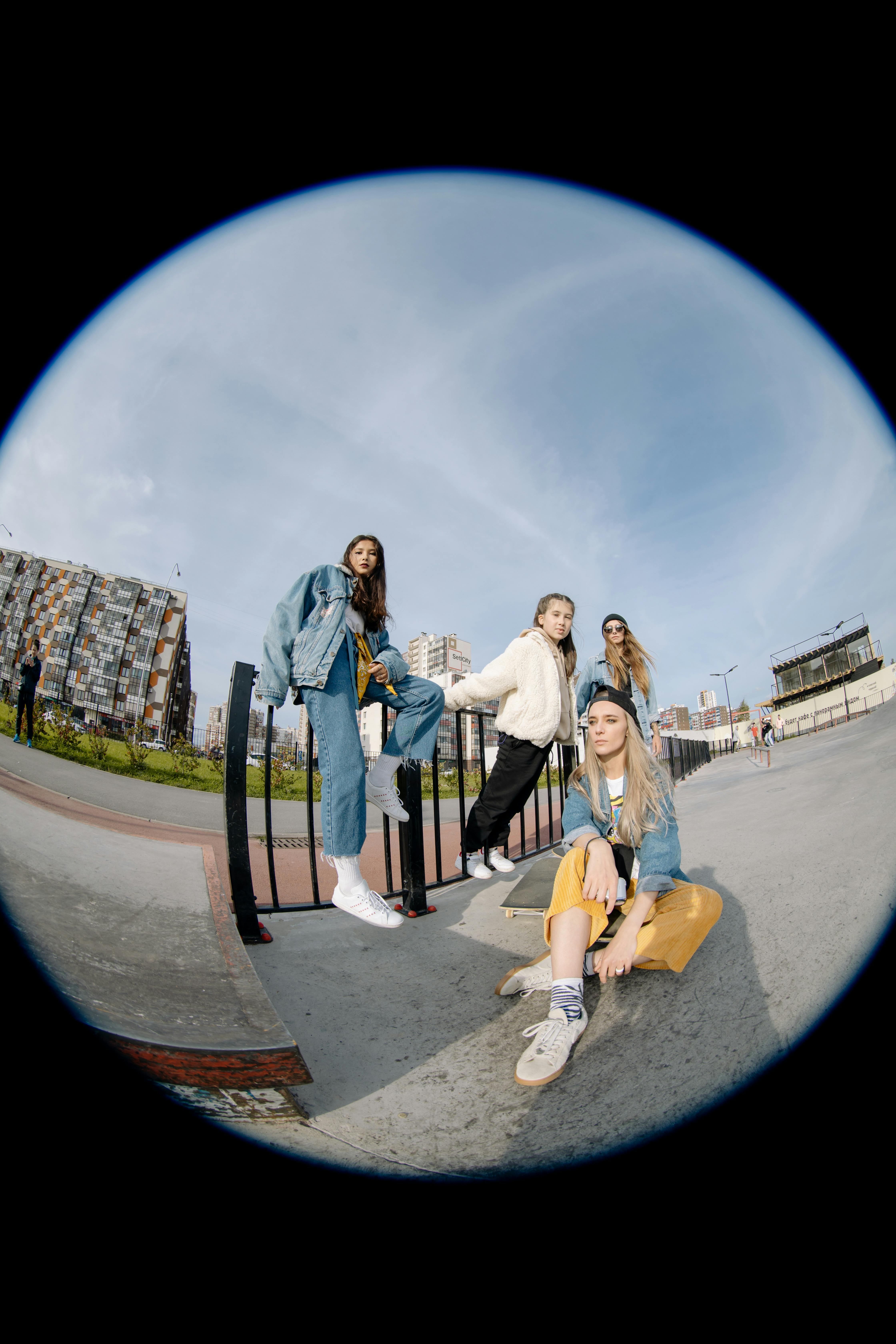 A group of young women exuding camaraderie and style at an urban skate park, captured with a fisheye lens.