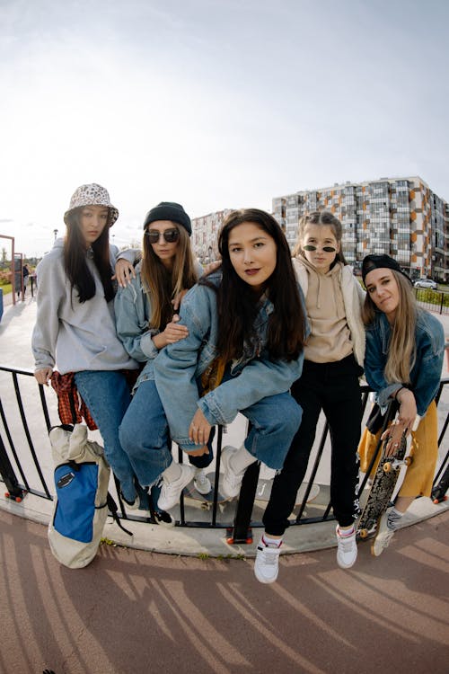 Free Group of Teenage Girls Sitting and Leaning on Metal Railing Stock Photo