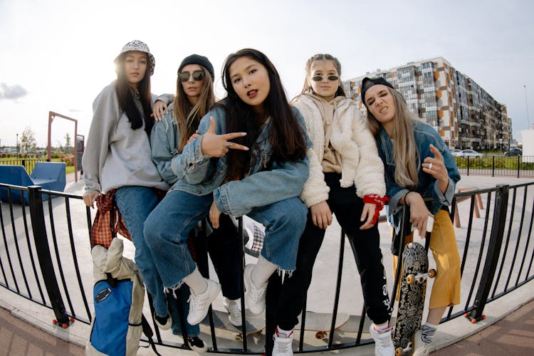 Young Girls Sitting On Metal Fence