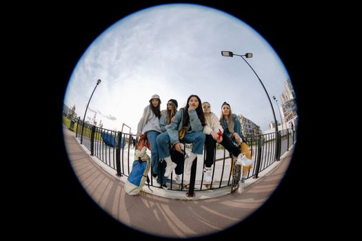 Group of young women sitting by a railing, enjoying a sunny day together.