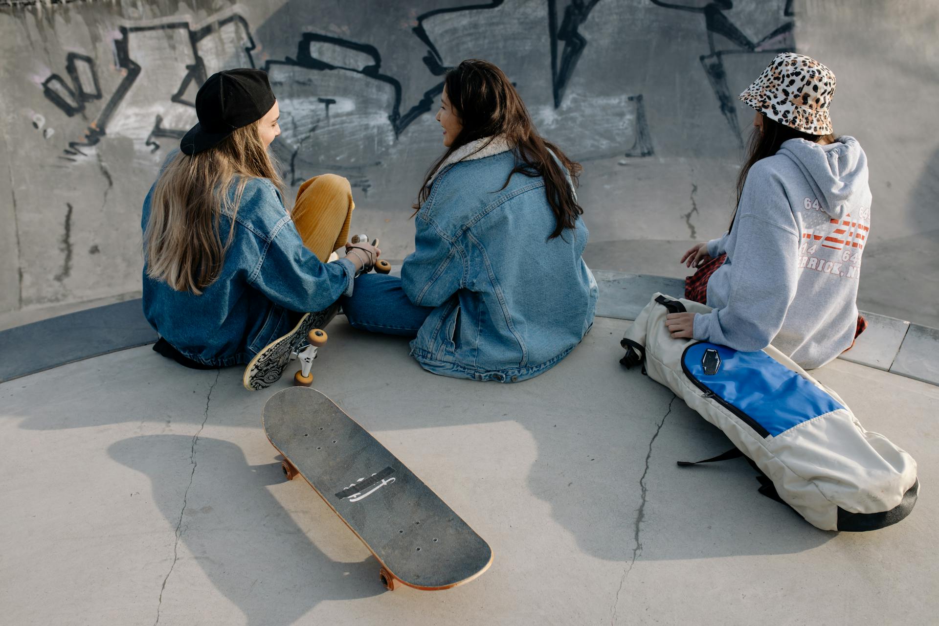 Group of Teenage Girls Wearing Jackets Sitting on Concrete Ground