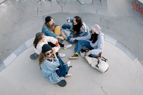 Free Group of Friends Having Fun Sitting on Skate Park Stock Photo