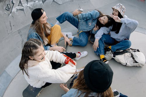 Free Group of Friends Having Fun Sitting on Skate Park Stock Photo