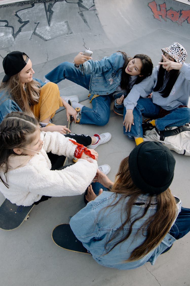 Young Girls Sitting On Concrete Pavement