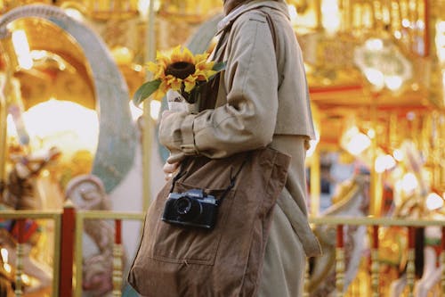 A Person in Brown Coat Holding a Sunflower
