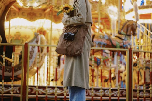 A Person in Brown Coat Holding a Sunflower
