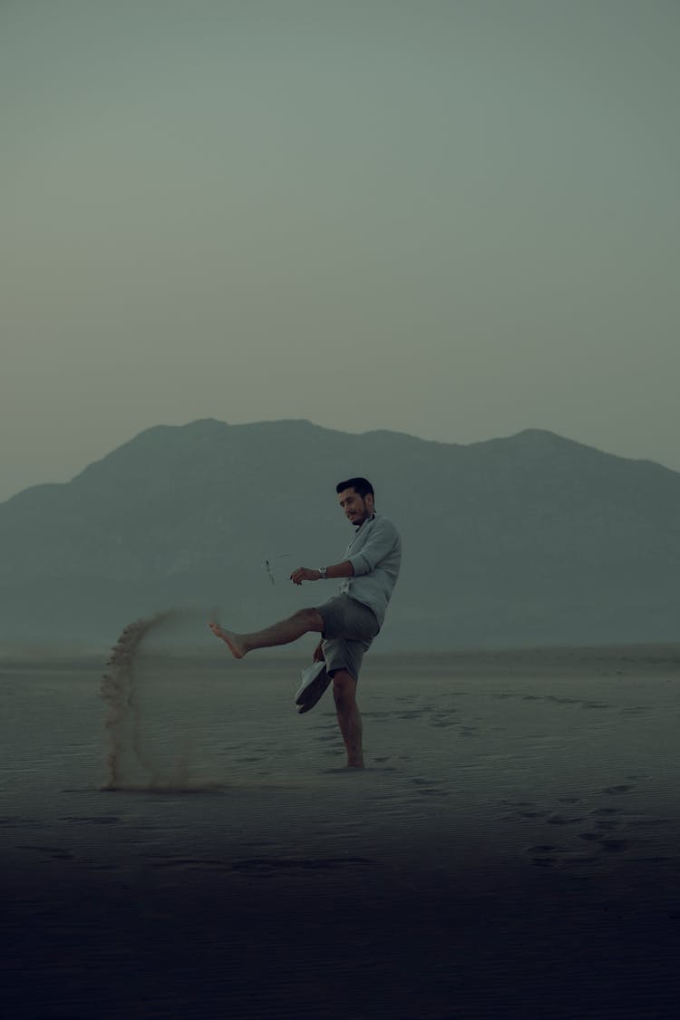 A Man Kicking Sand On Shore