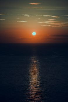 Beautiful sunset over the ocean with dramatic hues and reflective water surface.