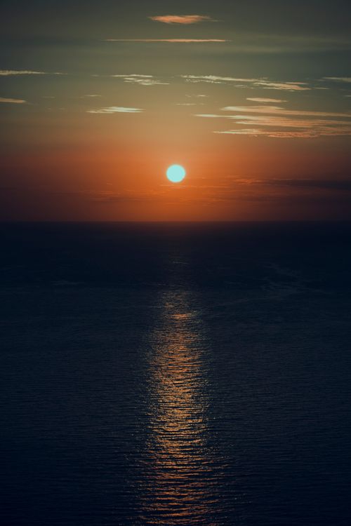 Free Beautiful sunset over the ocean with dramatic hues and reflective water surface. Stock Photo