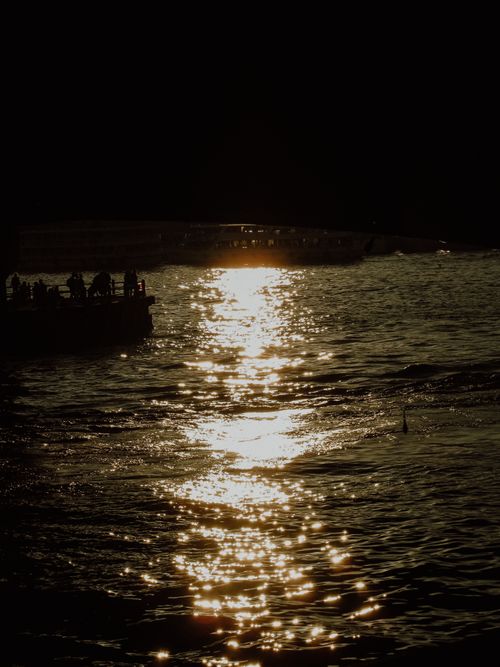 Free A moody sunset captures the silhouette of a boat and shimmering sea surface. Stock Photo