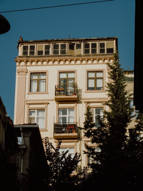 Free An impressive vintage apartment building with intricate design and glass windows under a clear blue sky. Stock Photo