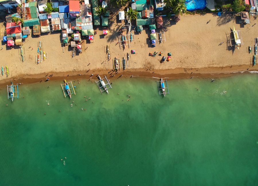 Captivating aerial view of a vibrant sandy beach with docked boats in the Philippines.